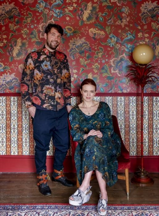 The House of Hackney founders Frieda and Javi in front of one of their wallpaper patterns.