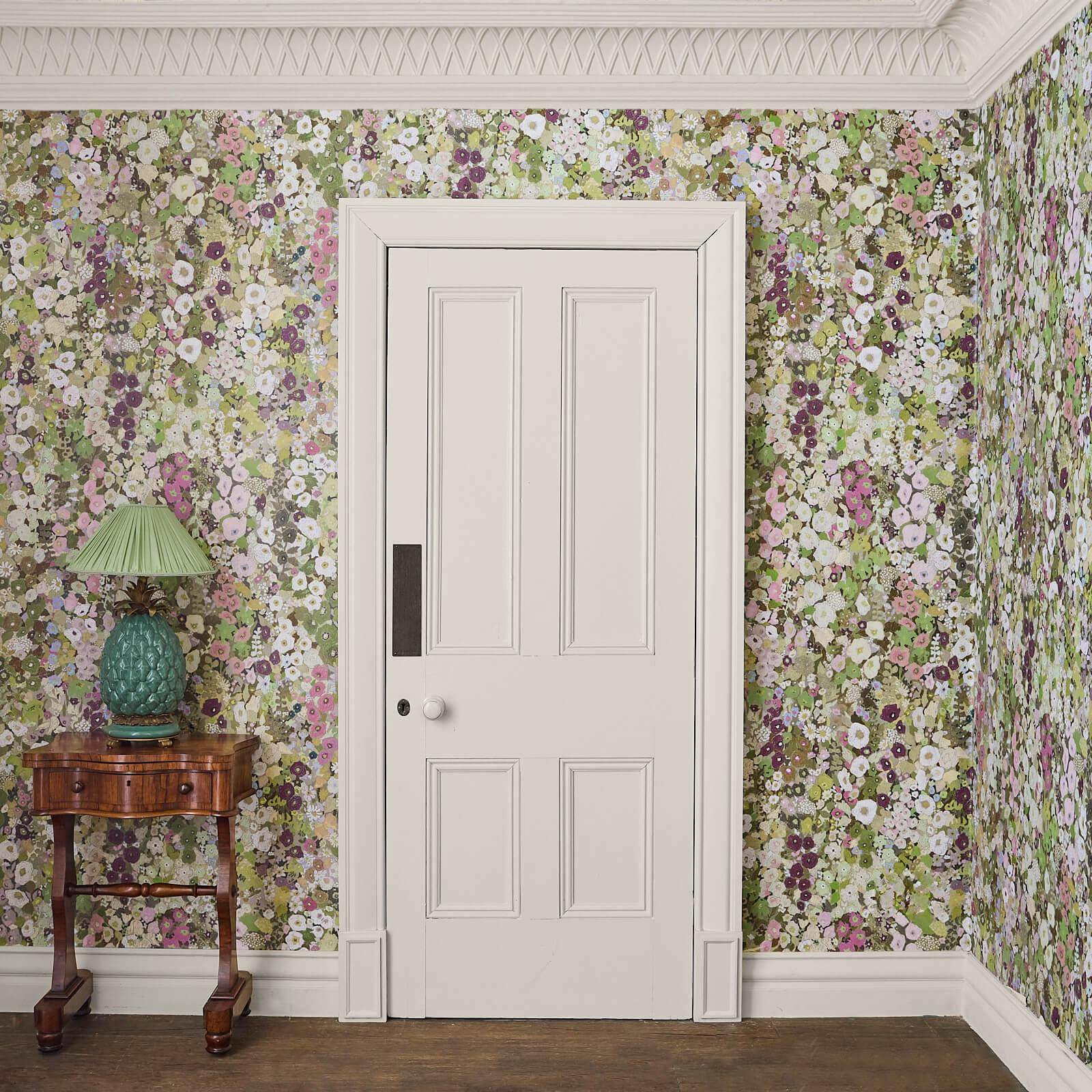 Floral Hollyhocks wallpapered room with a white door and wooden side table.
