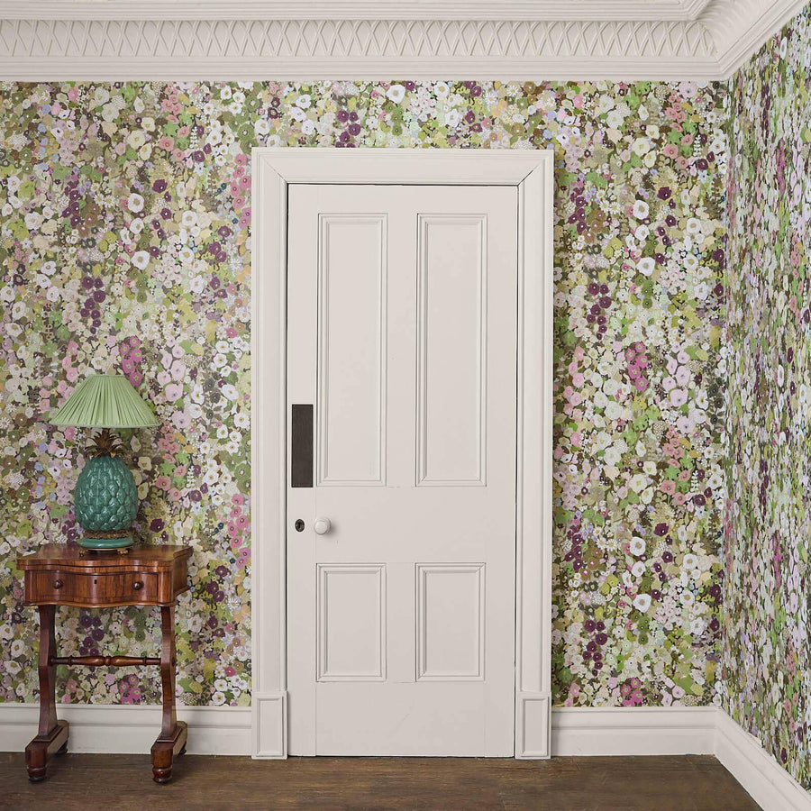 Floral Hollyhocks wallpapered room with a white door and wooden side table.