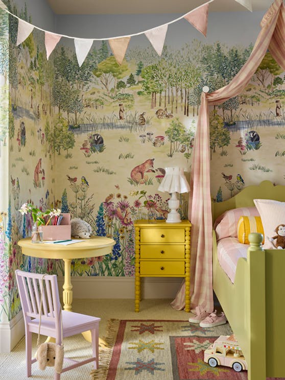 Children's bedroom with colorful wallpaper, yellow desk, and pink chair.